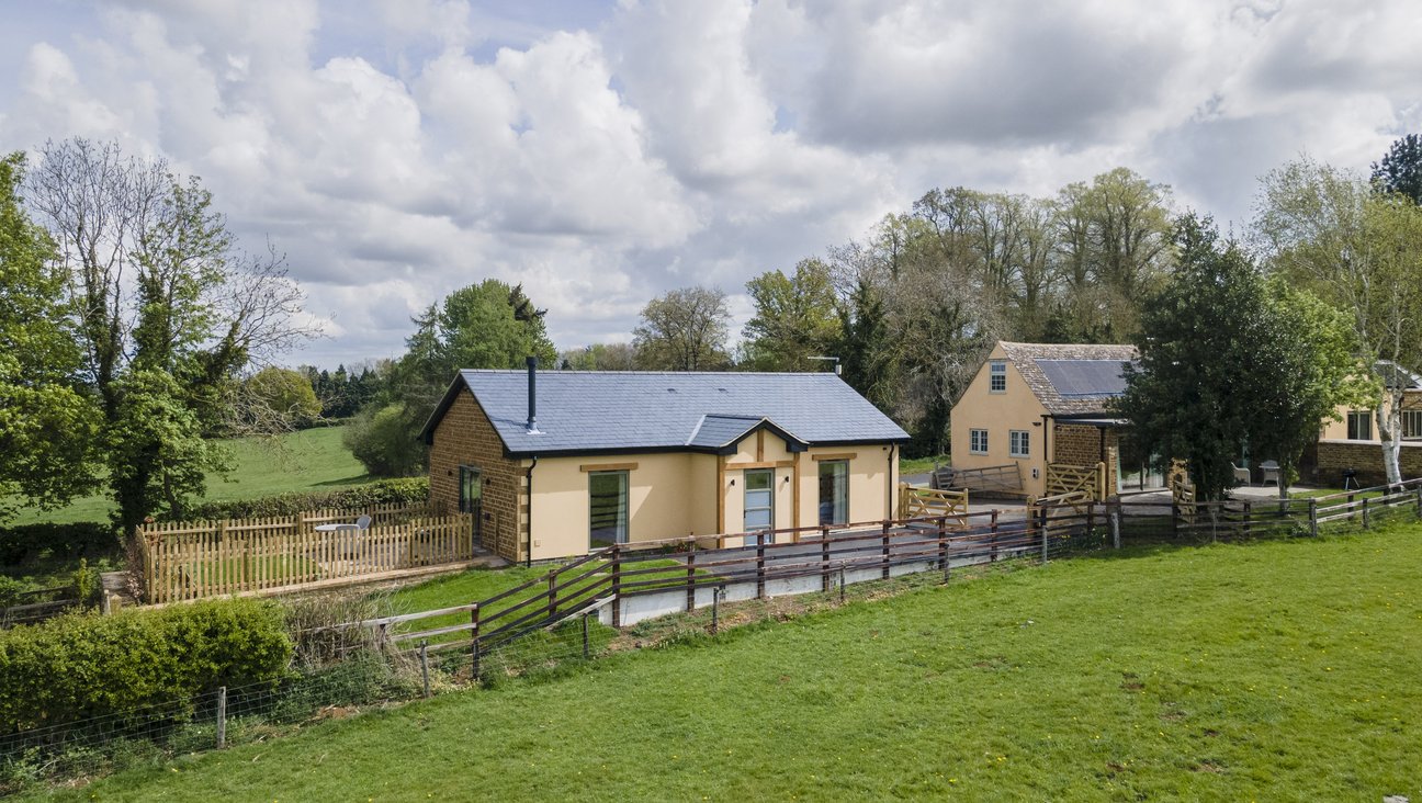 

                                        A beautifully built single story ironstone property with a slate roof and pale green windows. perched on a bank above the road this luxury property has panoramic views of old trees in park land.
