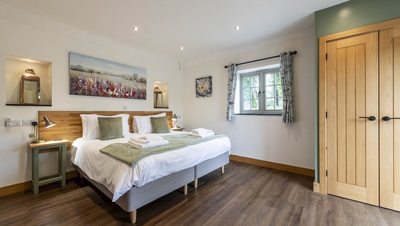 

                                        super king sized or twin beds made up with white linen and pale green throws and cusions. oak headboard flanked by alcoves with copper lanterns in them and hand made beside tables with lamps on them