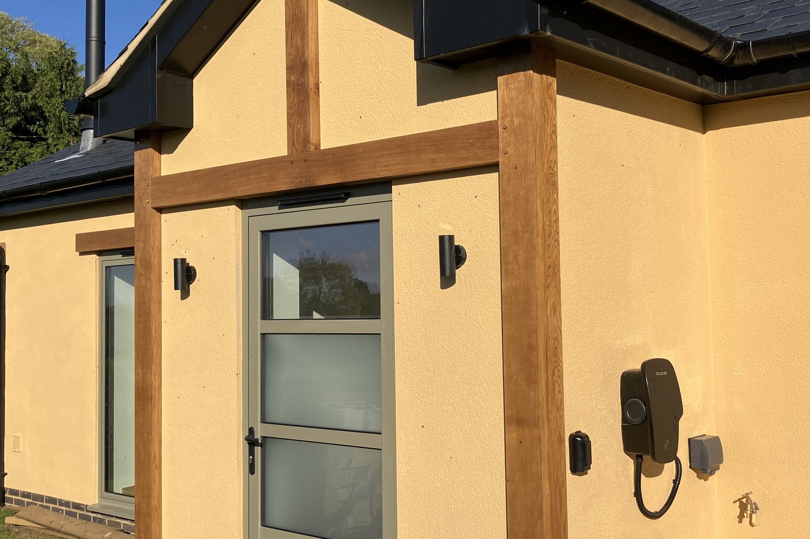 golden rendered cottage with oak porch and car charger, outside tap and socket to right of door