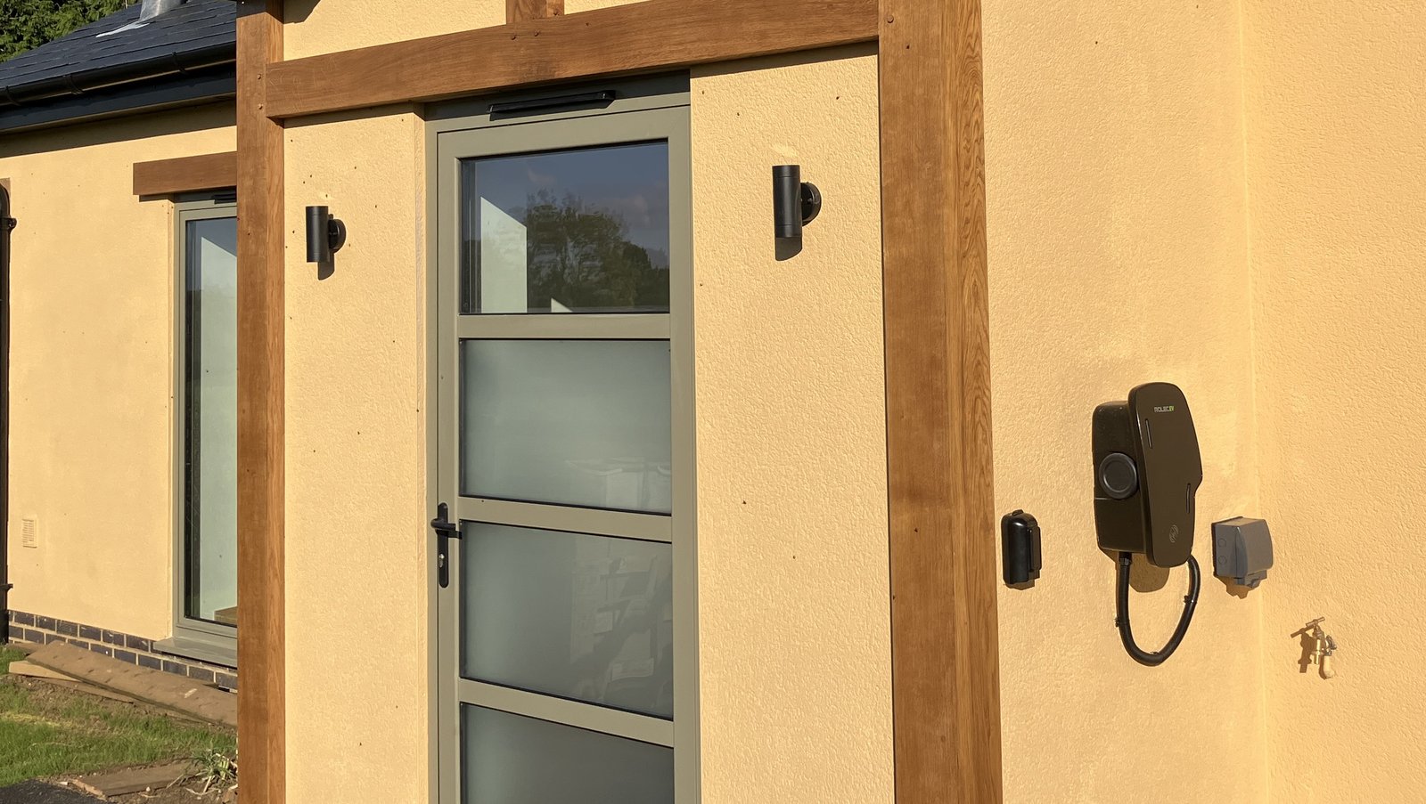 golden rendered cottage with oak porch and car charger, outside tap and socket to right of door