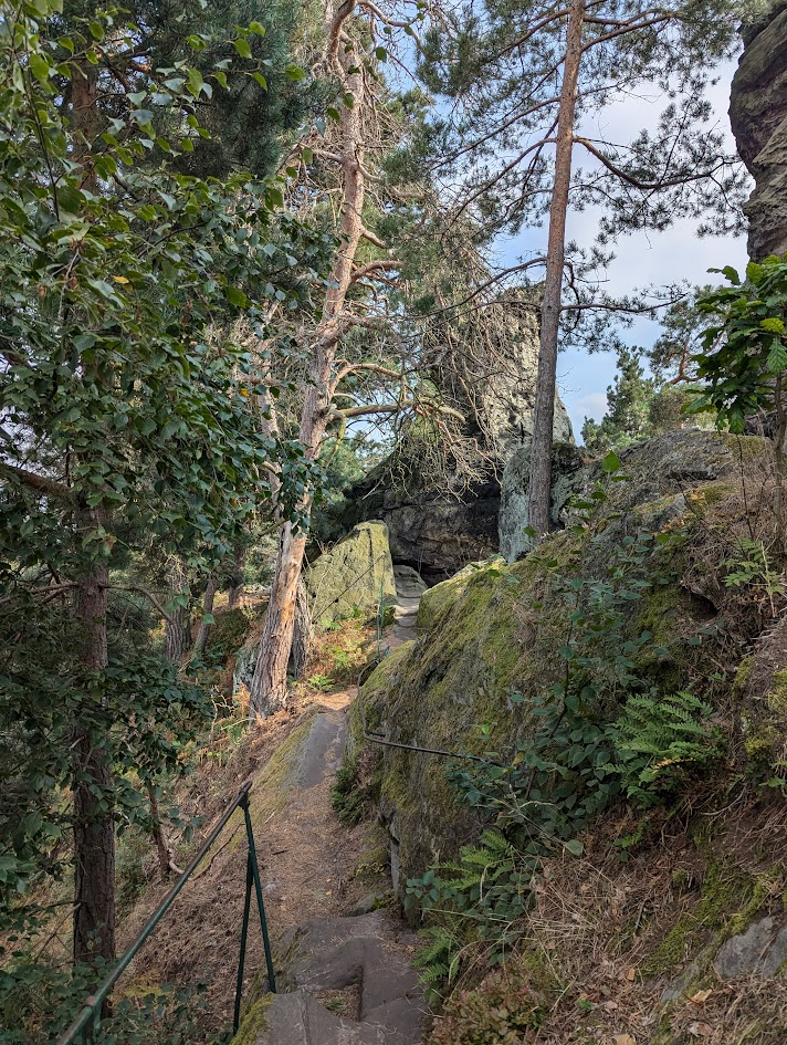 A narrow footpath, with rock formations on the right and a steep slope to the left.