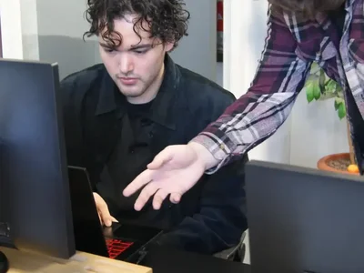 Een begeleider wijst een student iets aan op het scherm