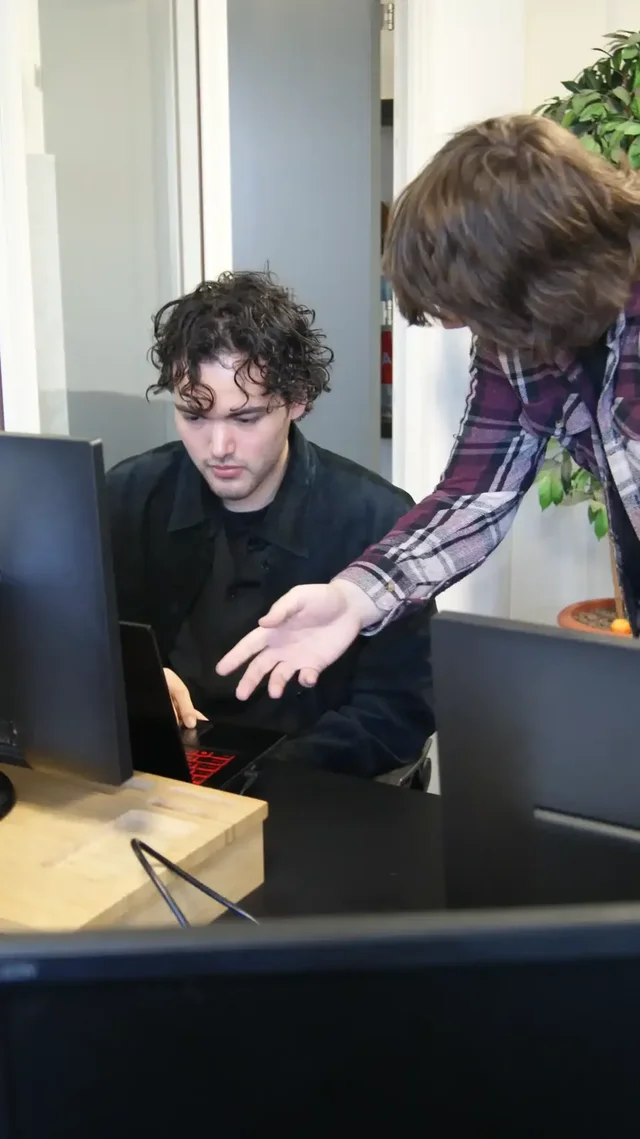 Een begeleider wijst een student iets aan op het scherm