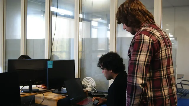 Studenten aan het werk op kantoor, een collega kijkt mee