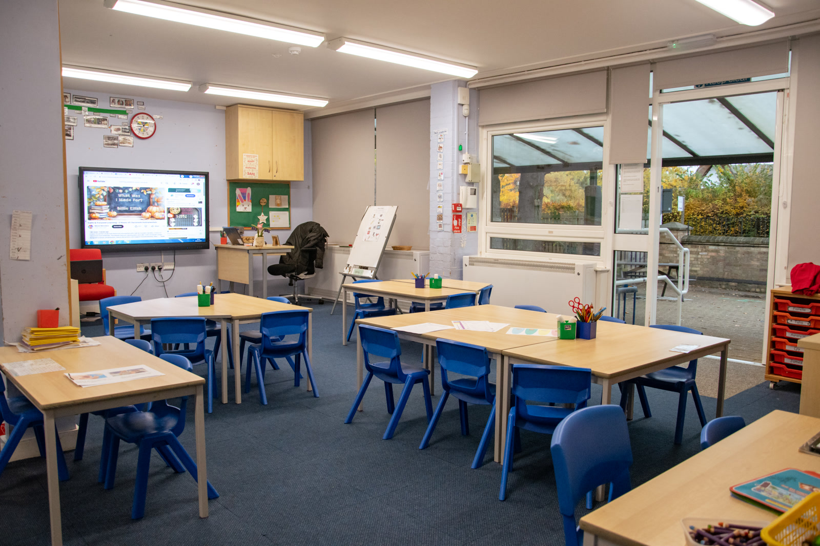 Empty school classroom with tables, chairs and wall displays