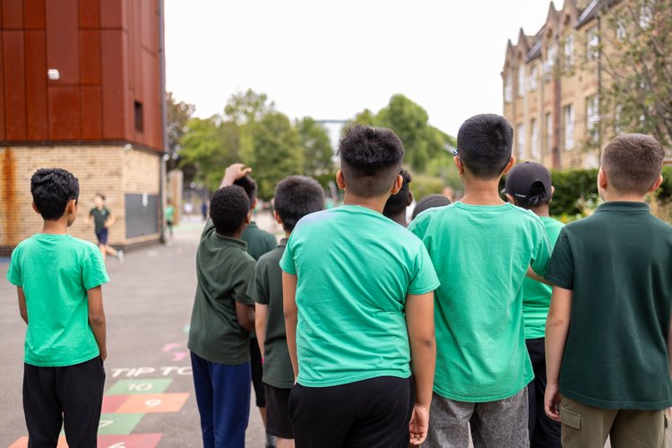 Pupils in the school playground, photographed from behind at Olga Primary School