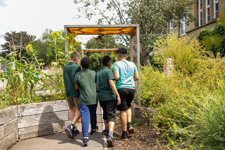 Pupils walking through the school garden, photographed from behind at Olga Primary School