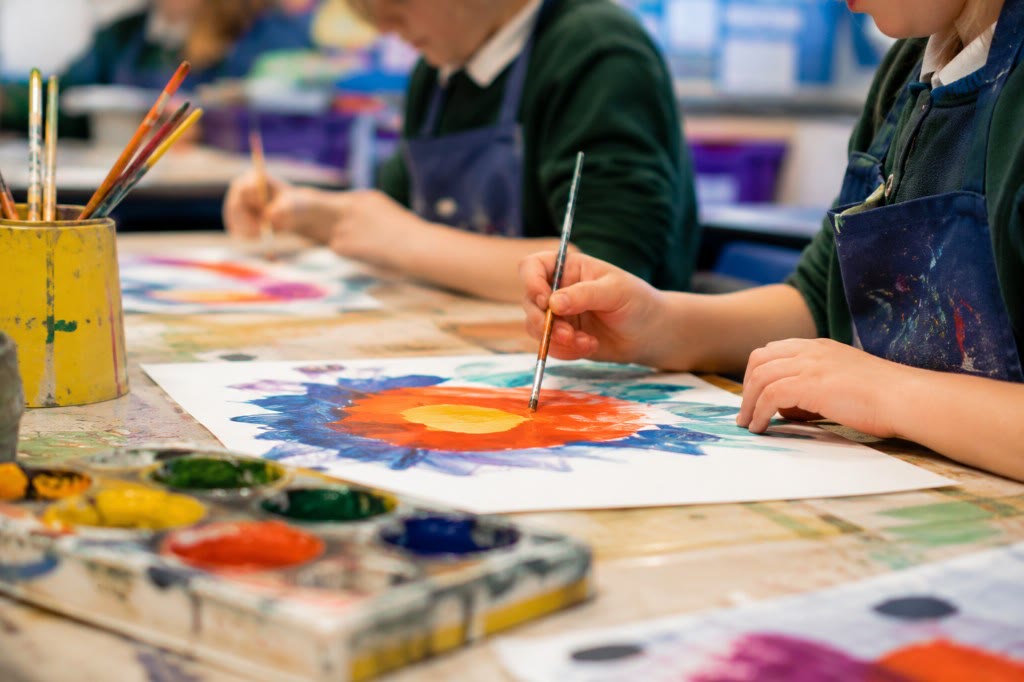 Close-up of a pupil painting a flower in art class, focusing on hands and activity rather than faces