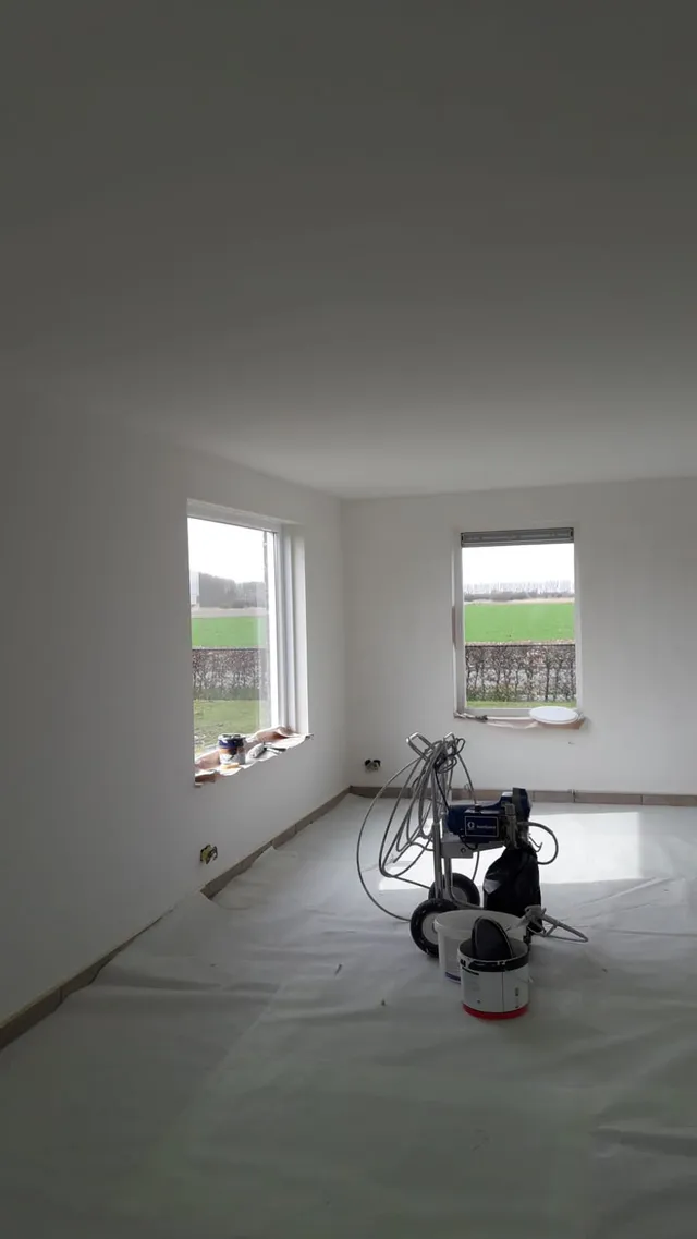 Een schilder spuit latex op een wand