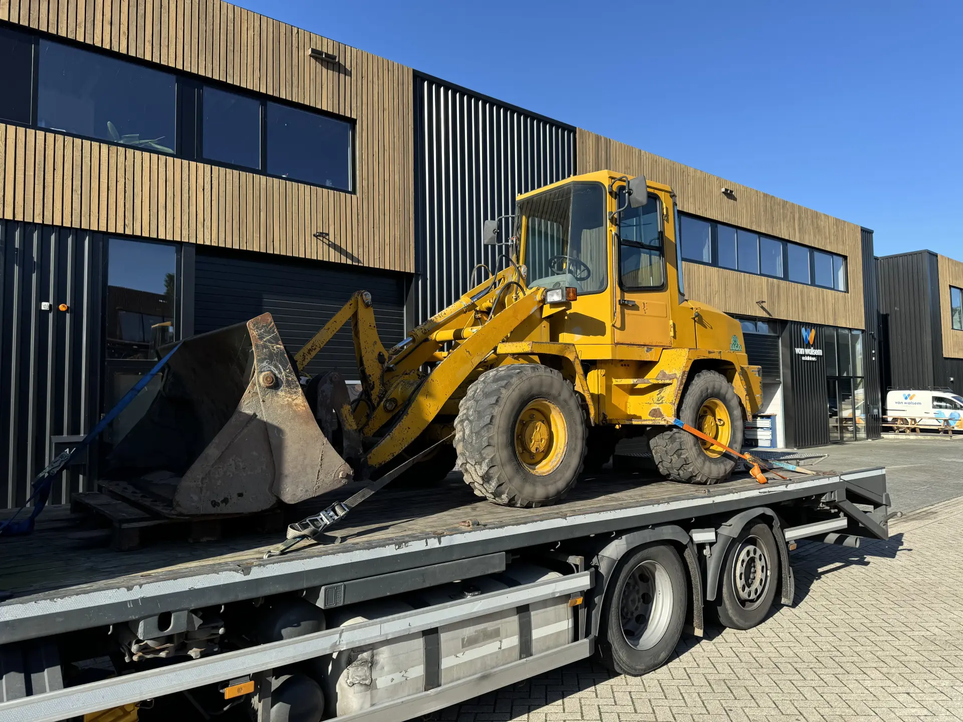 machinebod-shovel-wiellader-geel-op-transport