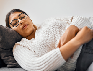 Women laying on the sofa holding her stomach