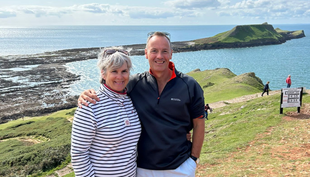 Sharon and her husband pose in front of the sea.