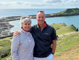 Sharon and her husband pose in front of the sea.