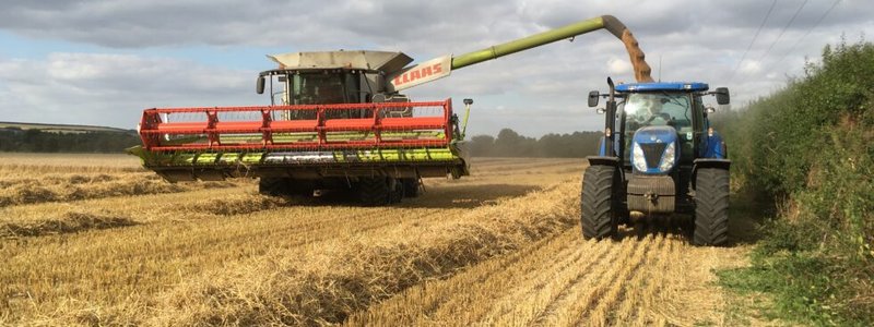 Tractor and combine harvester working in a field