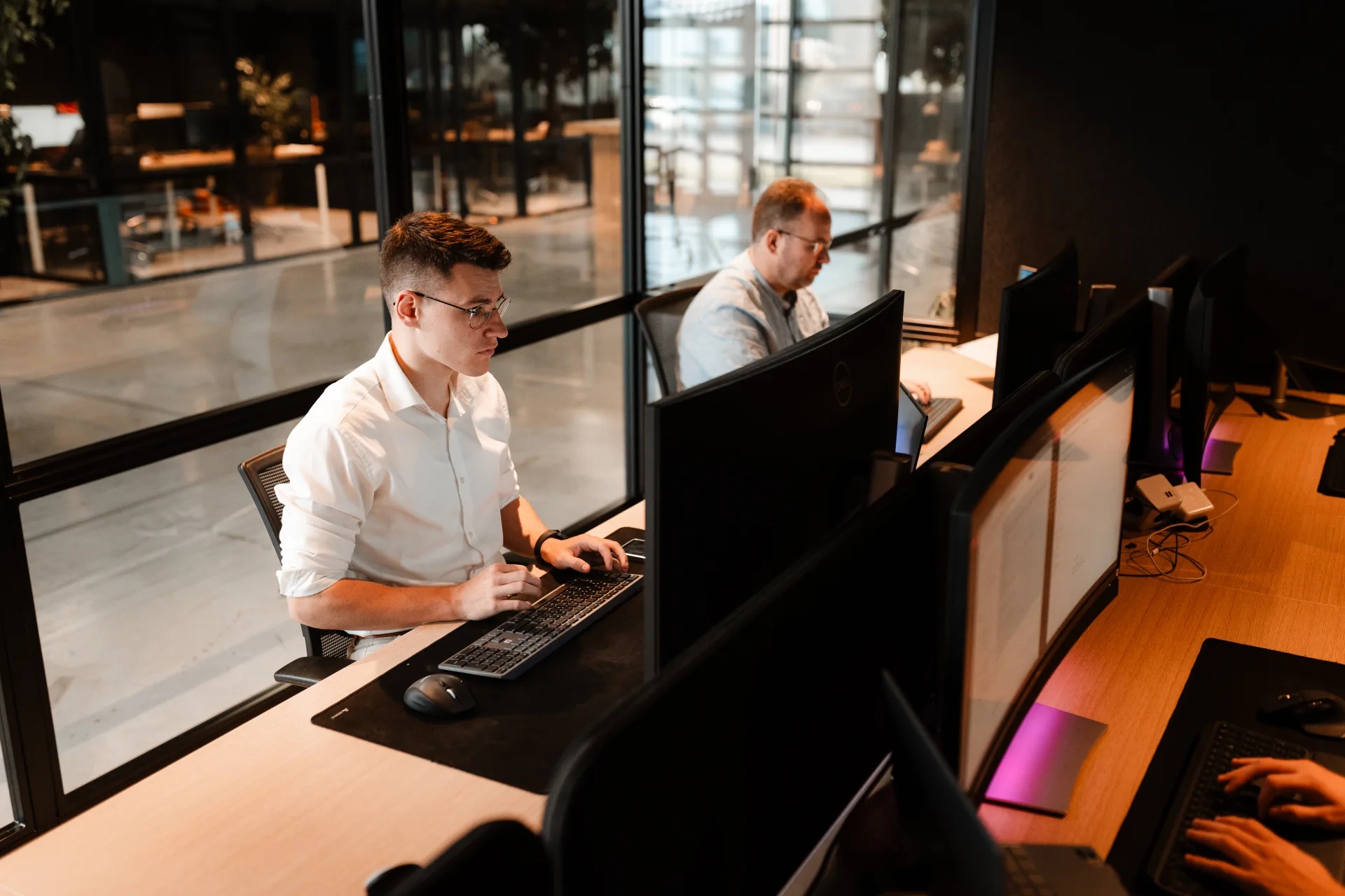 Developer aan het werk met live dashboard, kantoor met uitzicht op de werkvloer