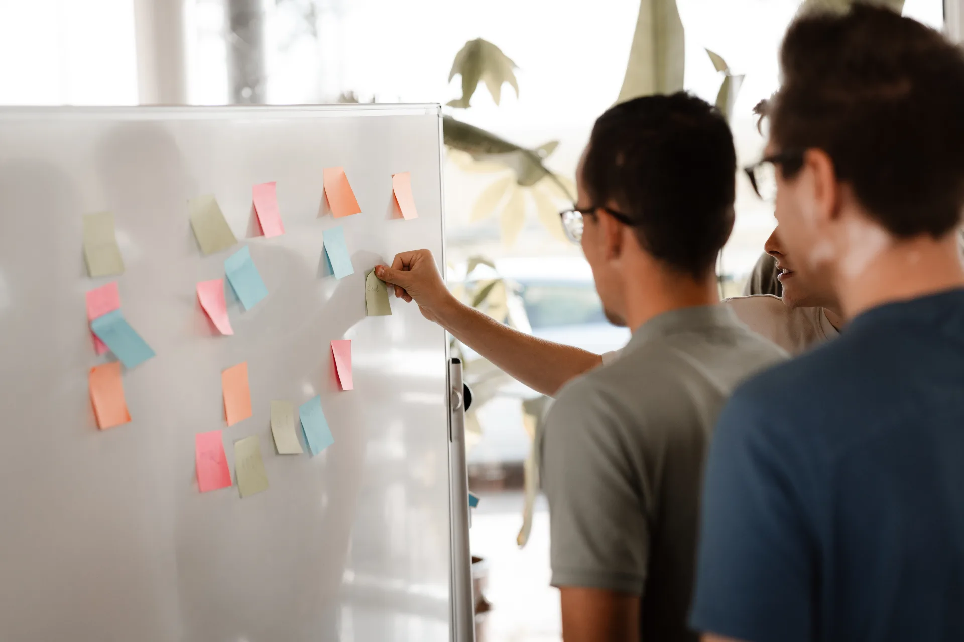 Twee developers sparren over sticky notes vol ideeën op een whiteboard