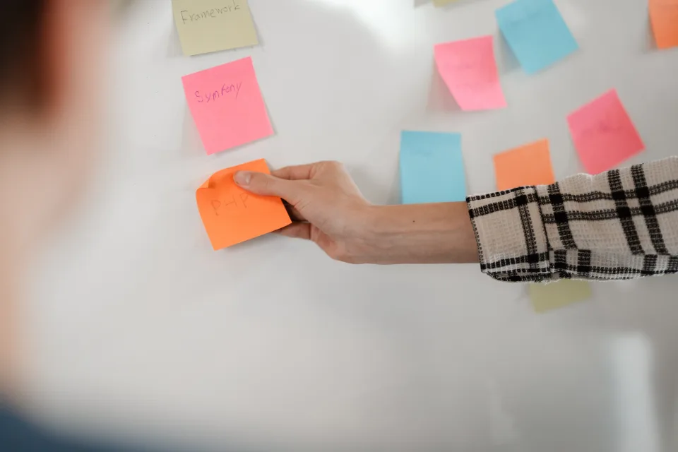 Teamlid ordent kleurrijke notities op whiteboard tijdens een productie-sessie