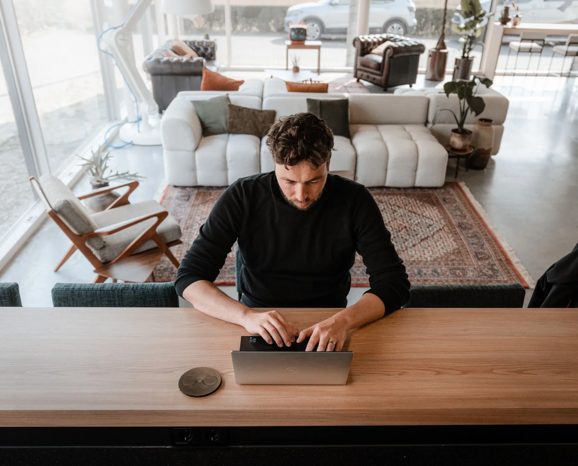 Developer werkt solo aan een laptop in een lichte, open werkruimte met loungemeubels op de achtergrond