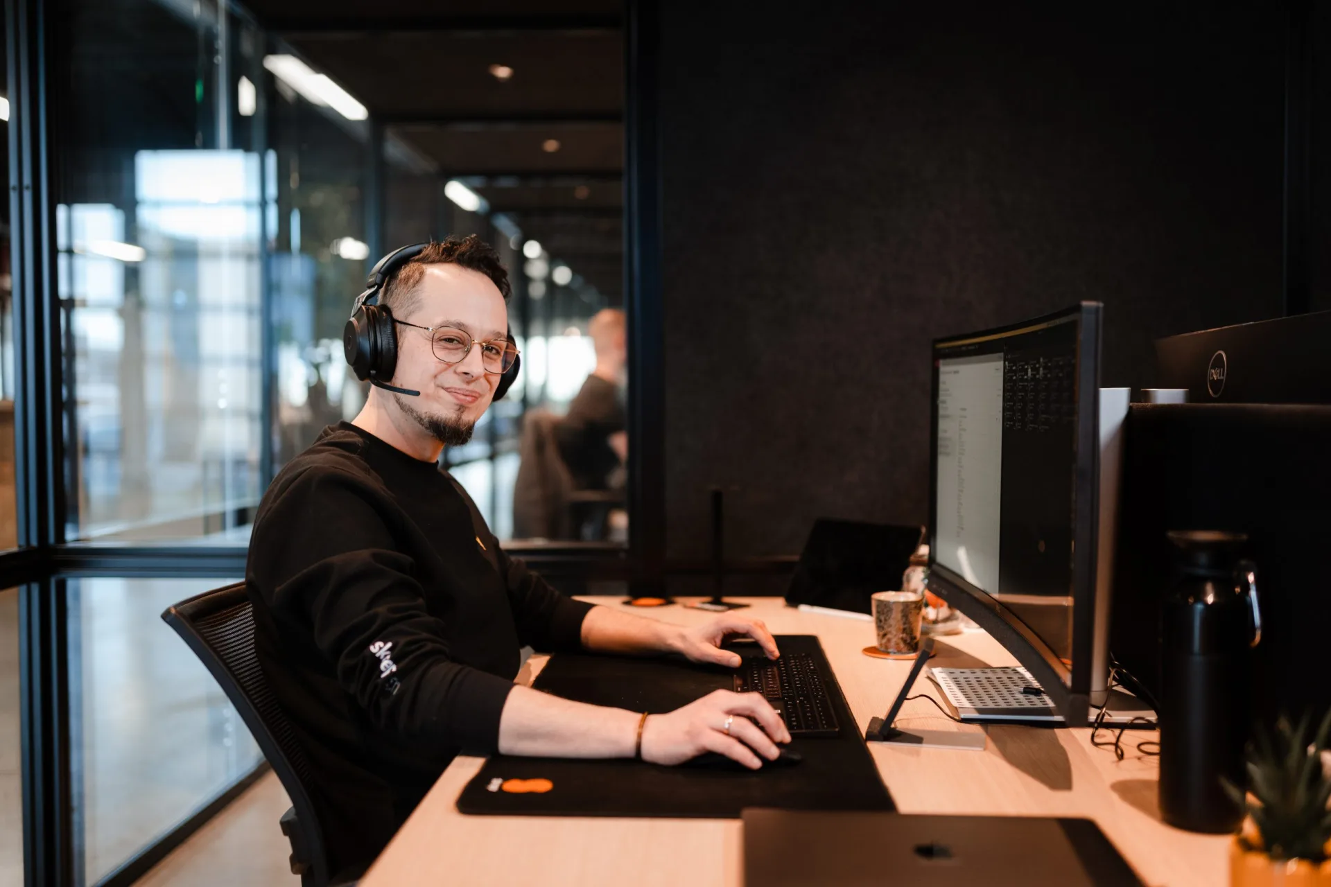 Developer met headset werkt aan live productie-data op twee Dell-monitors in een Skrepr-kantoor