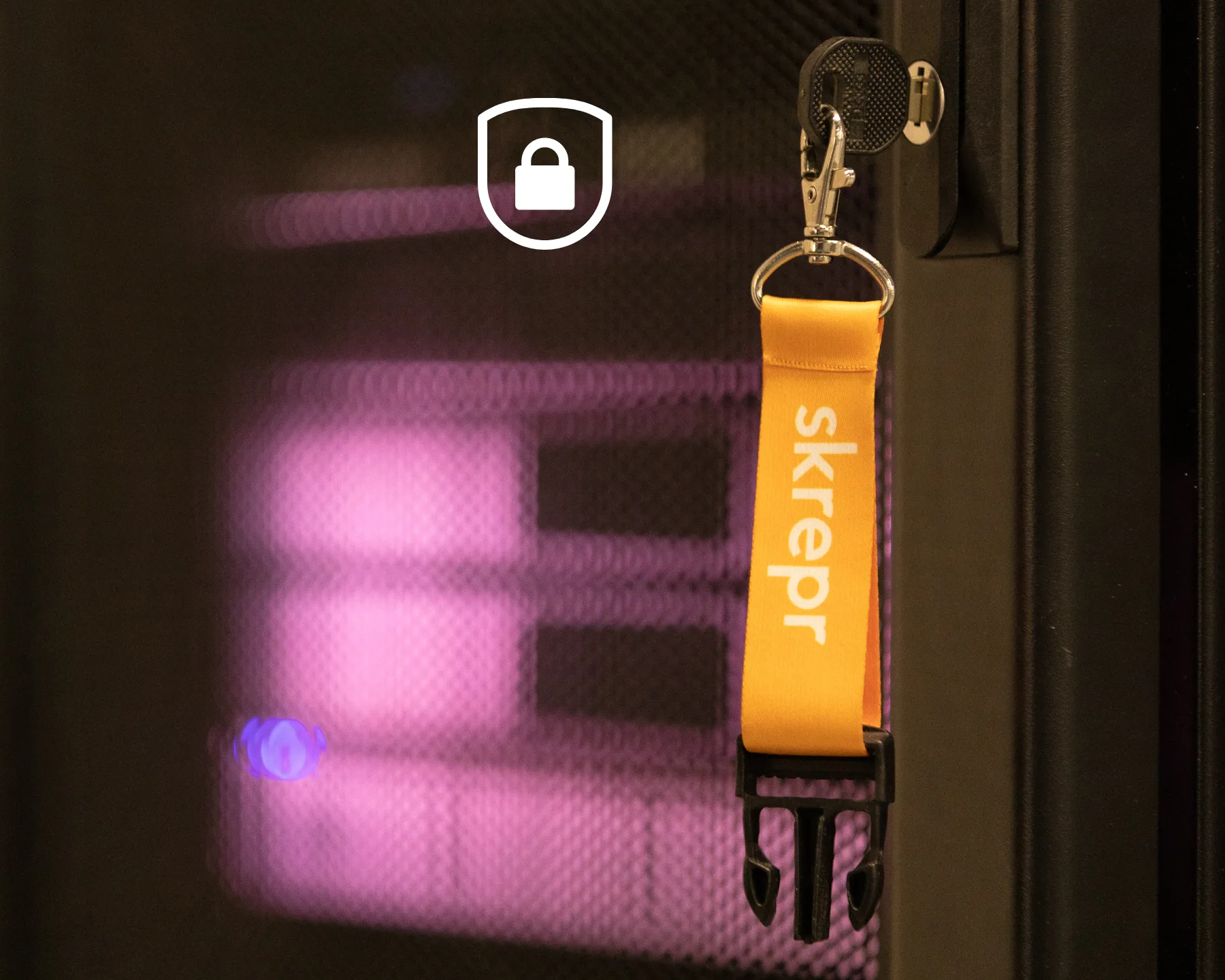 Skrepr-sleutelhanger met oranje label hangt in het slot van een serverrack in een datacenter