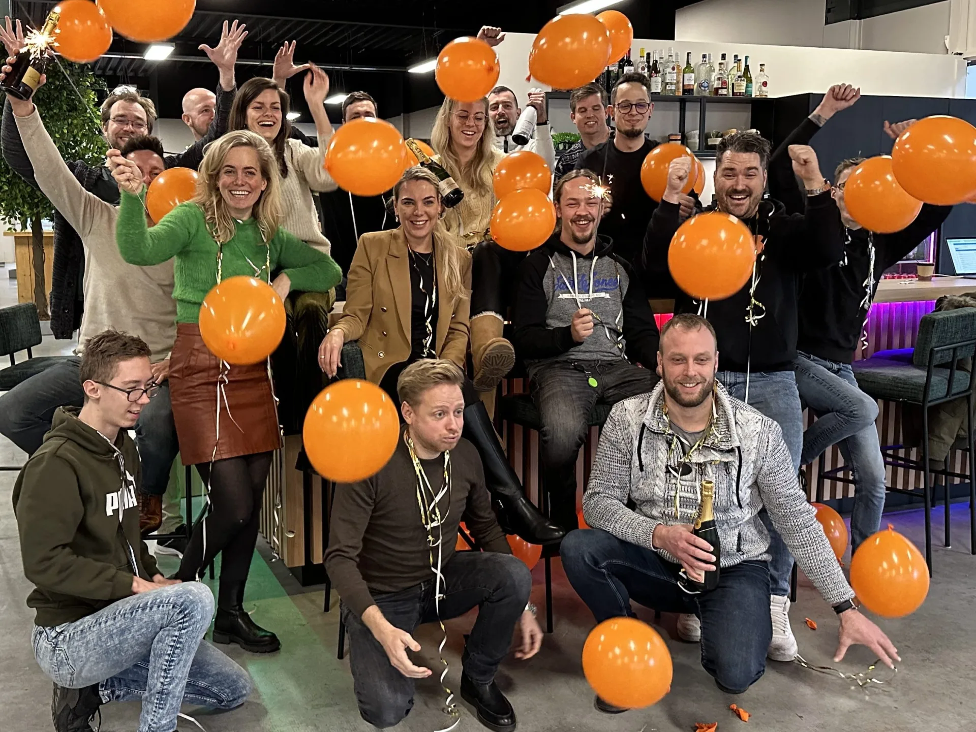 Het volledige Skrepr-team viert een mijlpaal met oranje ballonnen, sparklers en champagne in het kantoor op Urk