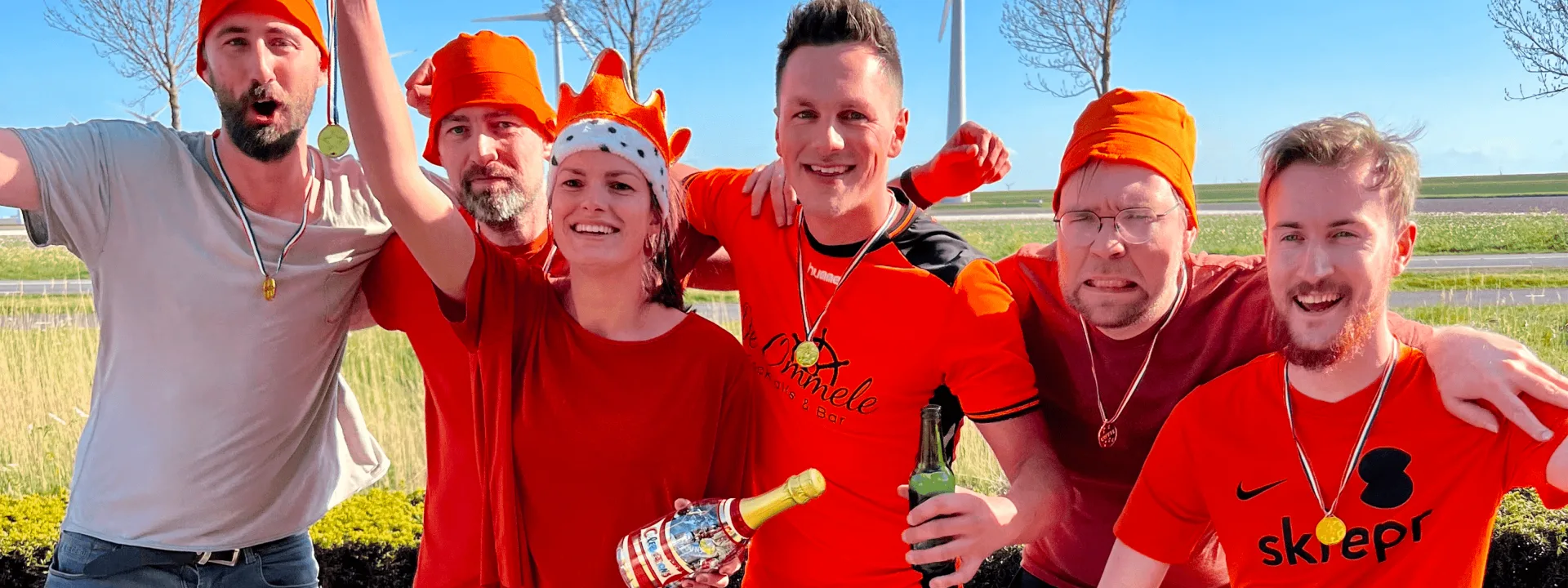 Het Skrepr-team viert de overwinning bij de Koningsspelen 2022, oranje outfits, medailles en kampioensgevoel