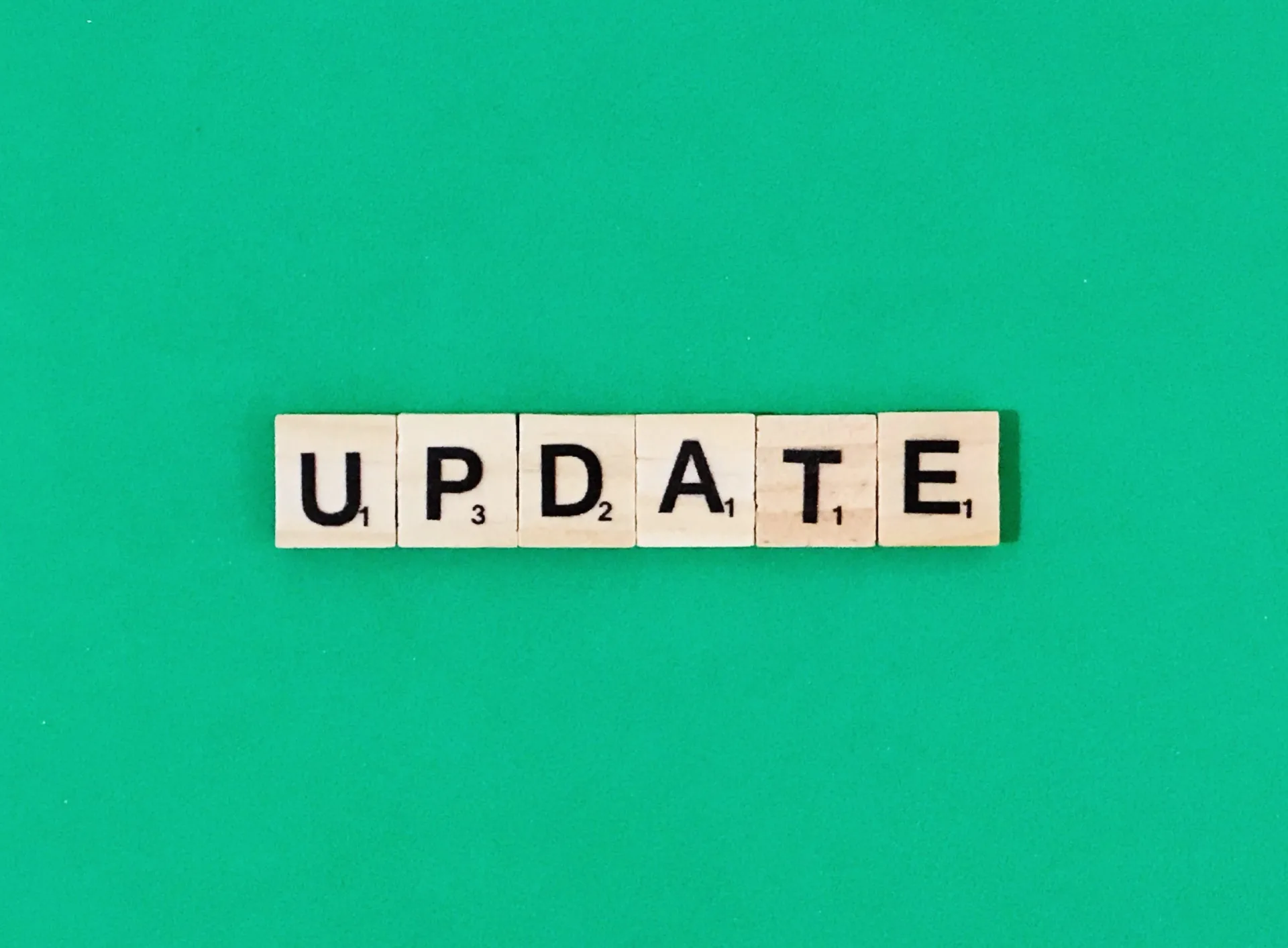 Scrabble-tegels spellen het woord UPDATE op een groen oppervlak