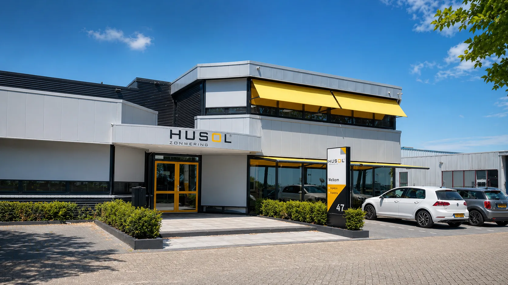 Exterieur van Husol Zonwering, een productiebedrijf met strakke gevel, gele markiezen en nette ingang op nummer 47