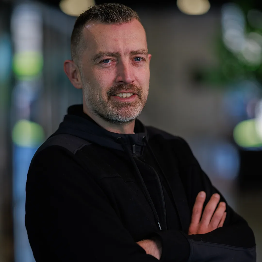 Skrepr-collega Ben staat zelfverzekerd met gevouwen armen, klaar voor het volgende project