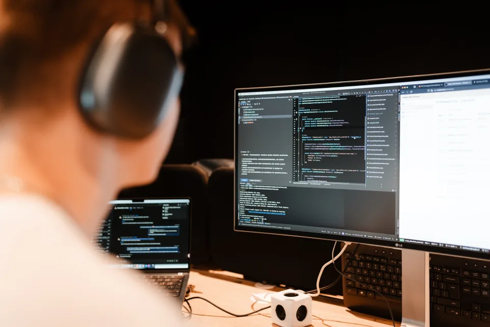 Developer werkt aan live dashboard met productie-code op meerdere schermen