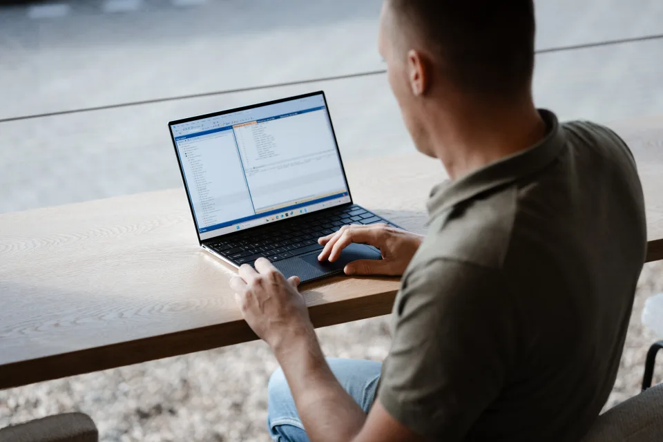 Developer werkt aan live productie-data op een laptop bij het raam