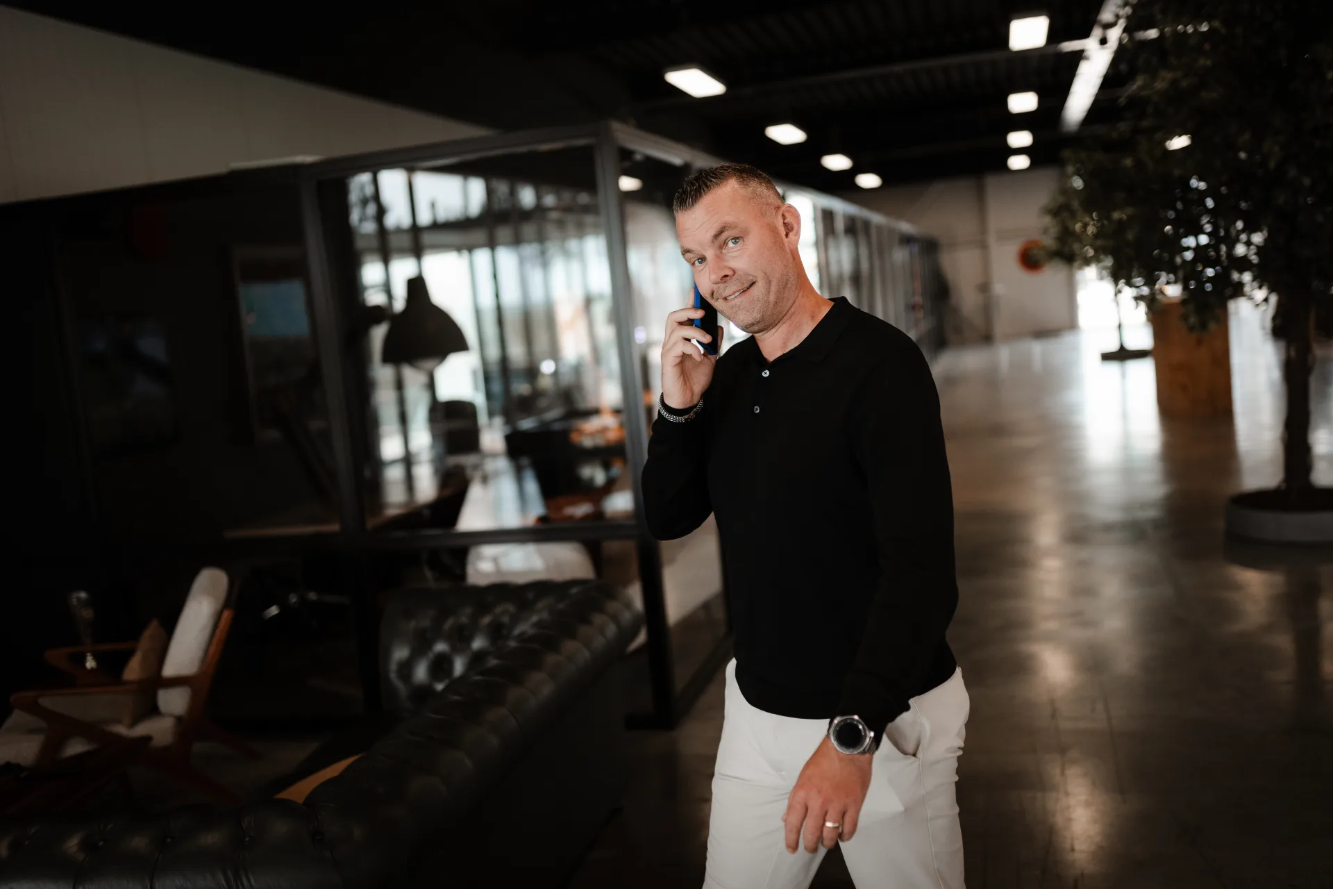 Developer met telefoon in het Skrepr-kantoor, omgeven door live dashboards en productie-data