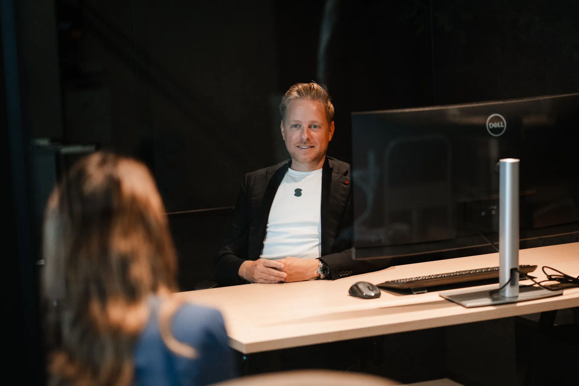 Developer werkt aan live productie-data op monitor, met collega in gesprek