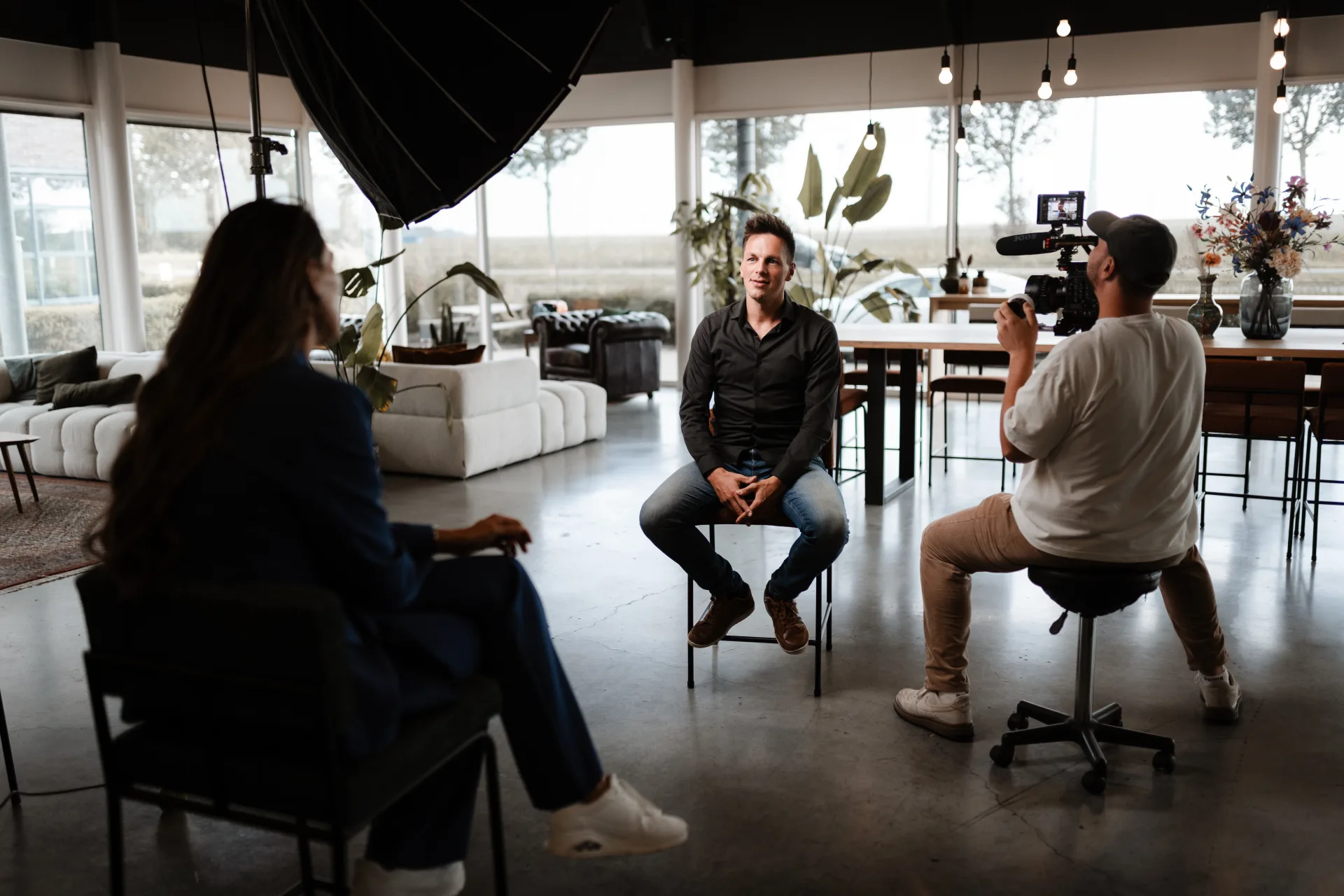 Cameraman filmt developer in gesprek met collega's rond productie-data op scherm