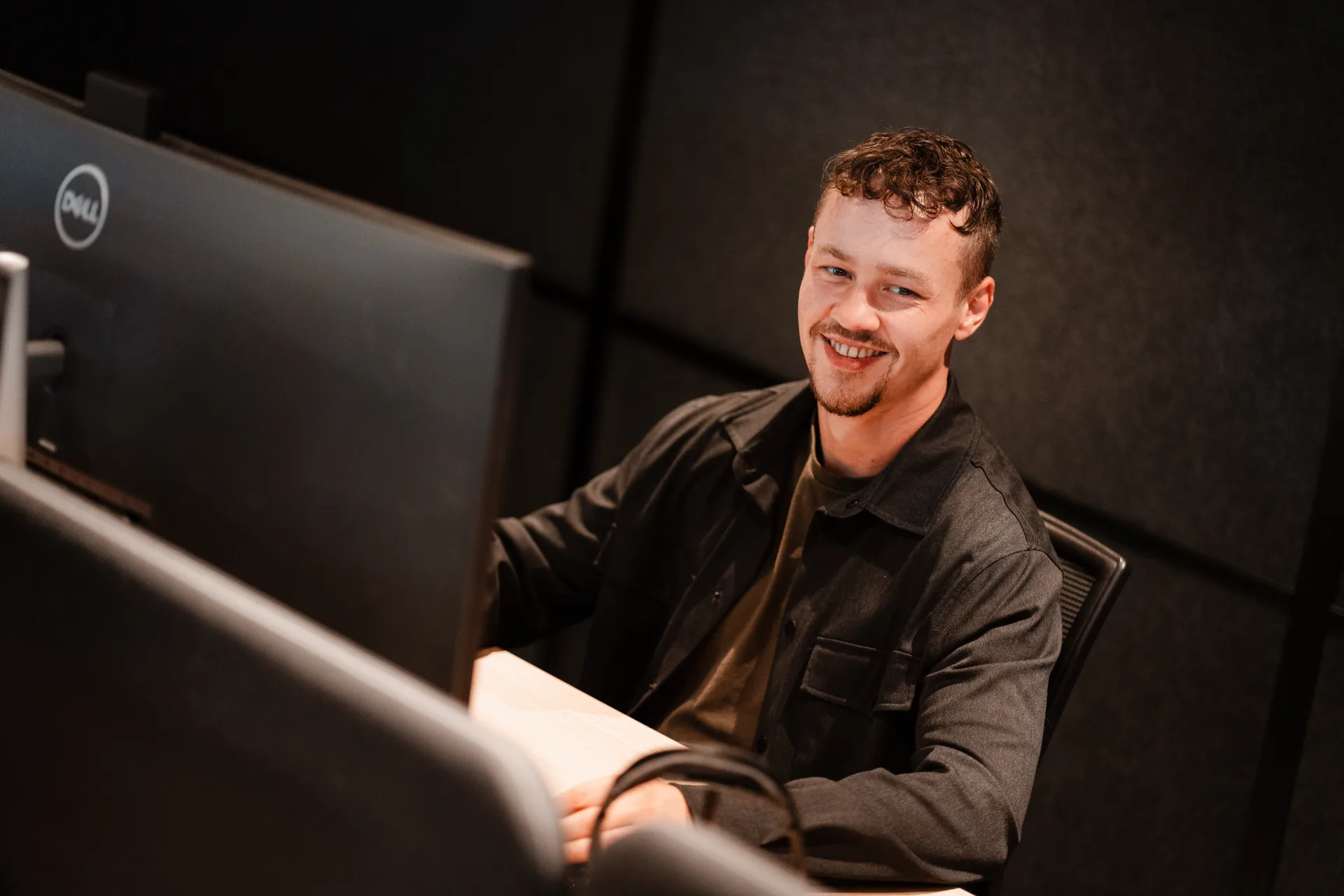 Developer werkt gefocust aan monitor met live productie-data en glimlacht