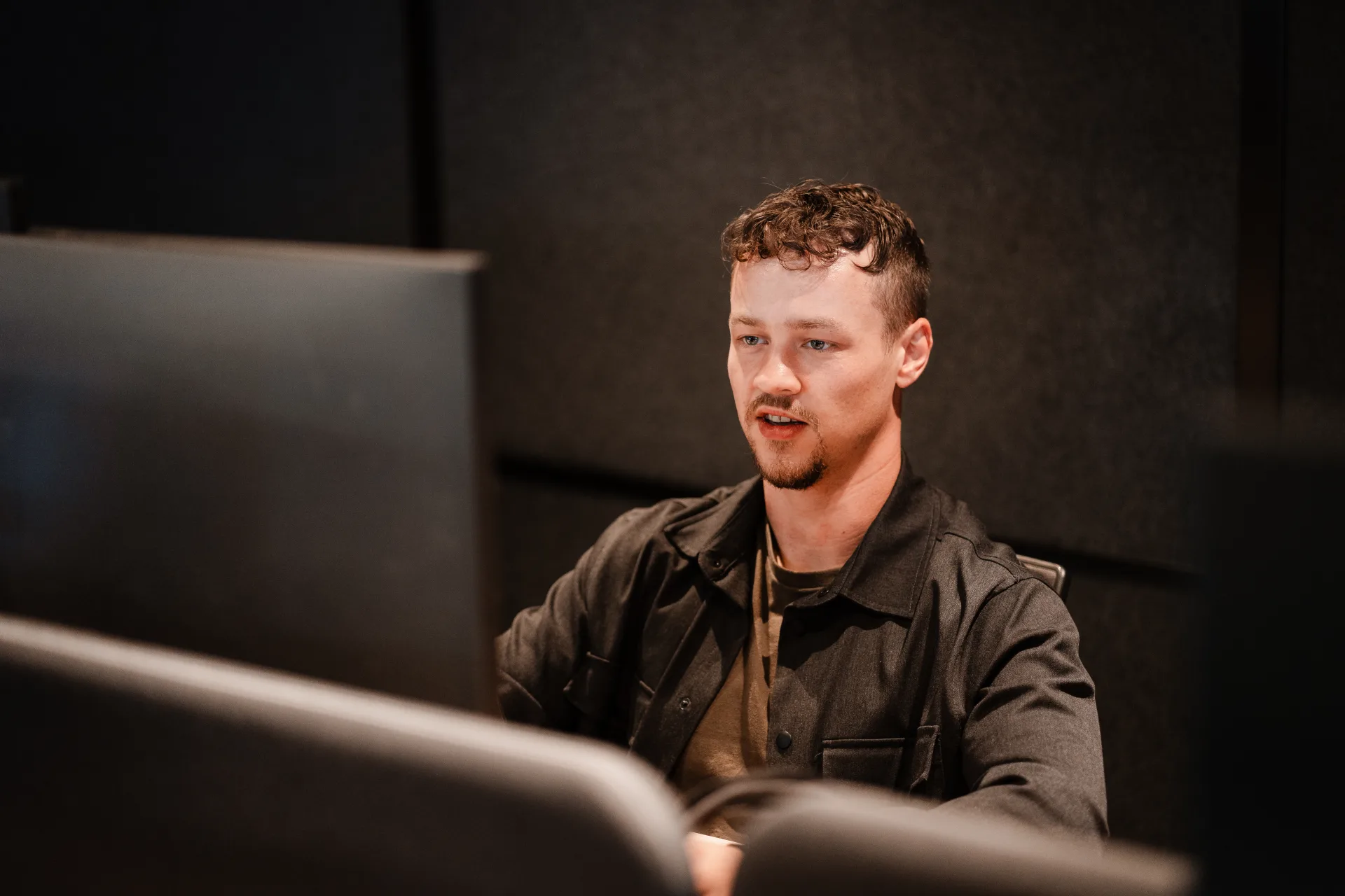 Developer werkt gefocust aan dashboard met real-time productie-informatie op grote monitor