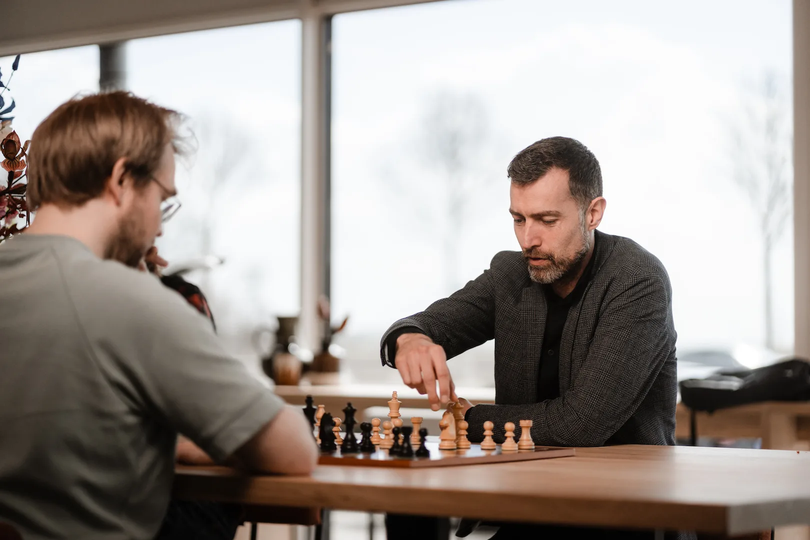 Twee collega's spelen schaak aan een tafel, diep geconcentreerd op de volgende zet