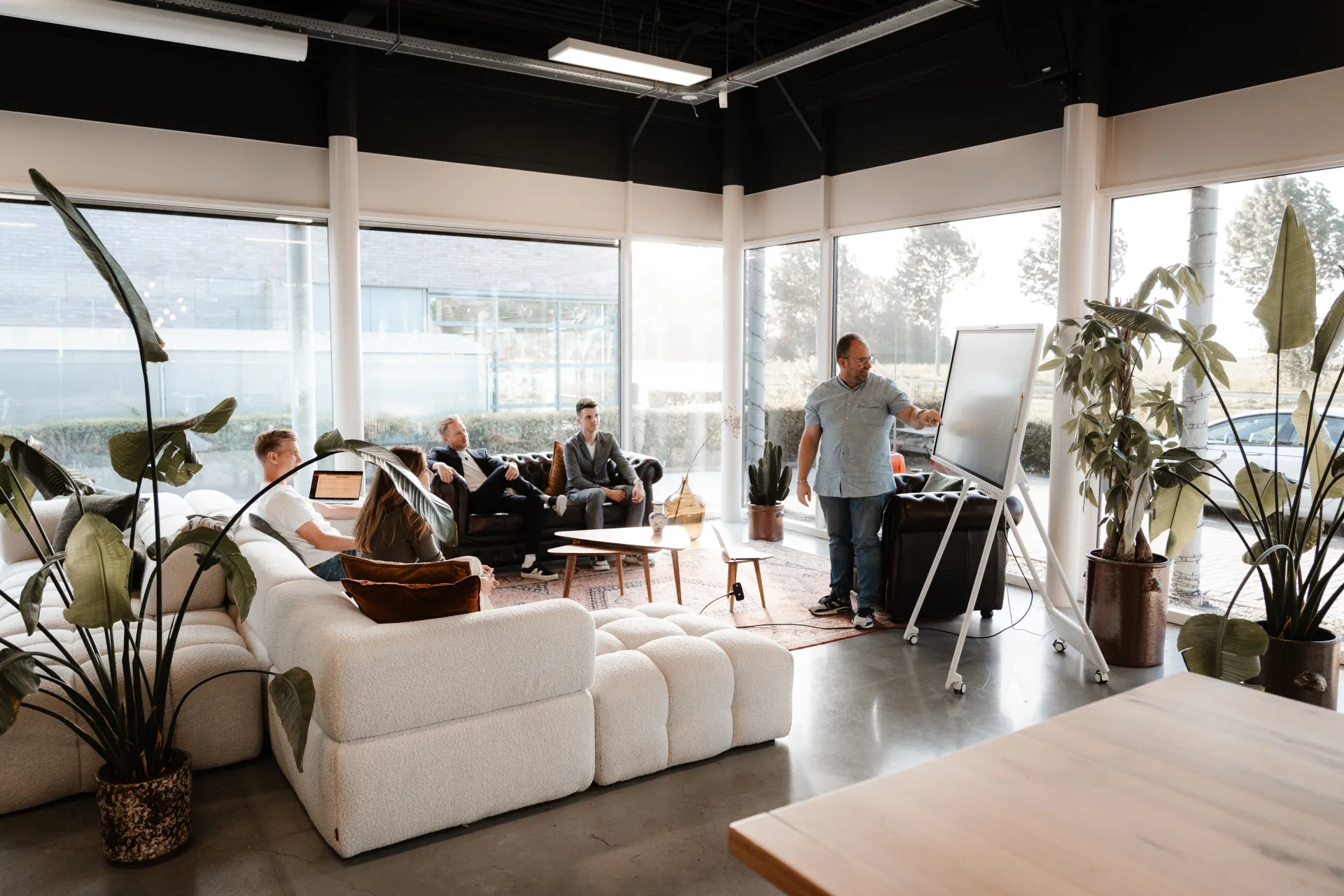 Team aan het werk in een lichte kantoorruimte met live dashboards en whiteboard-sessies