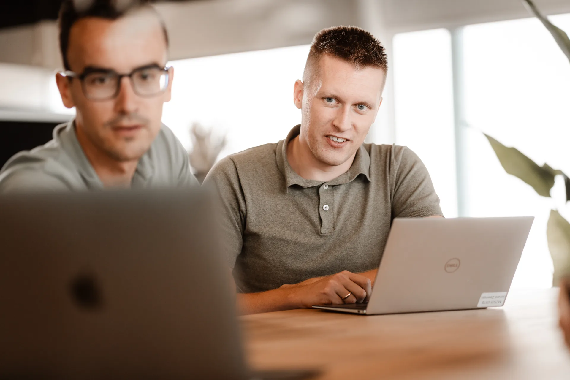 Twee developers werken aan live productie-data op laptops in een lichte werkruimte