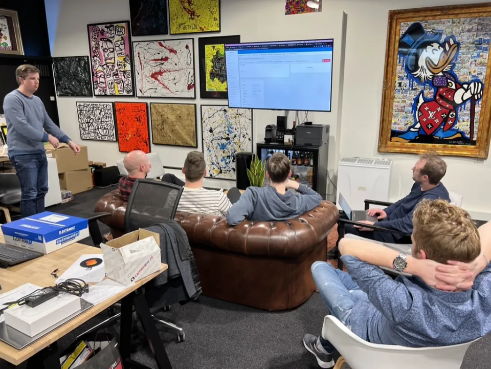 Skrepr-team in een informele sessie rond een groot scherm met live dashboard, één SLA voor werkplek en netwerk samen